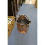 A COPPER FUEL BIN, with embossed decoration and swing handle raised on an oval base.