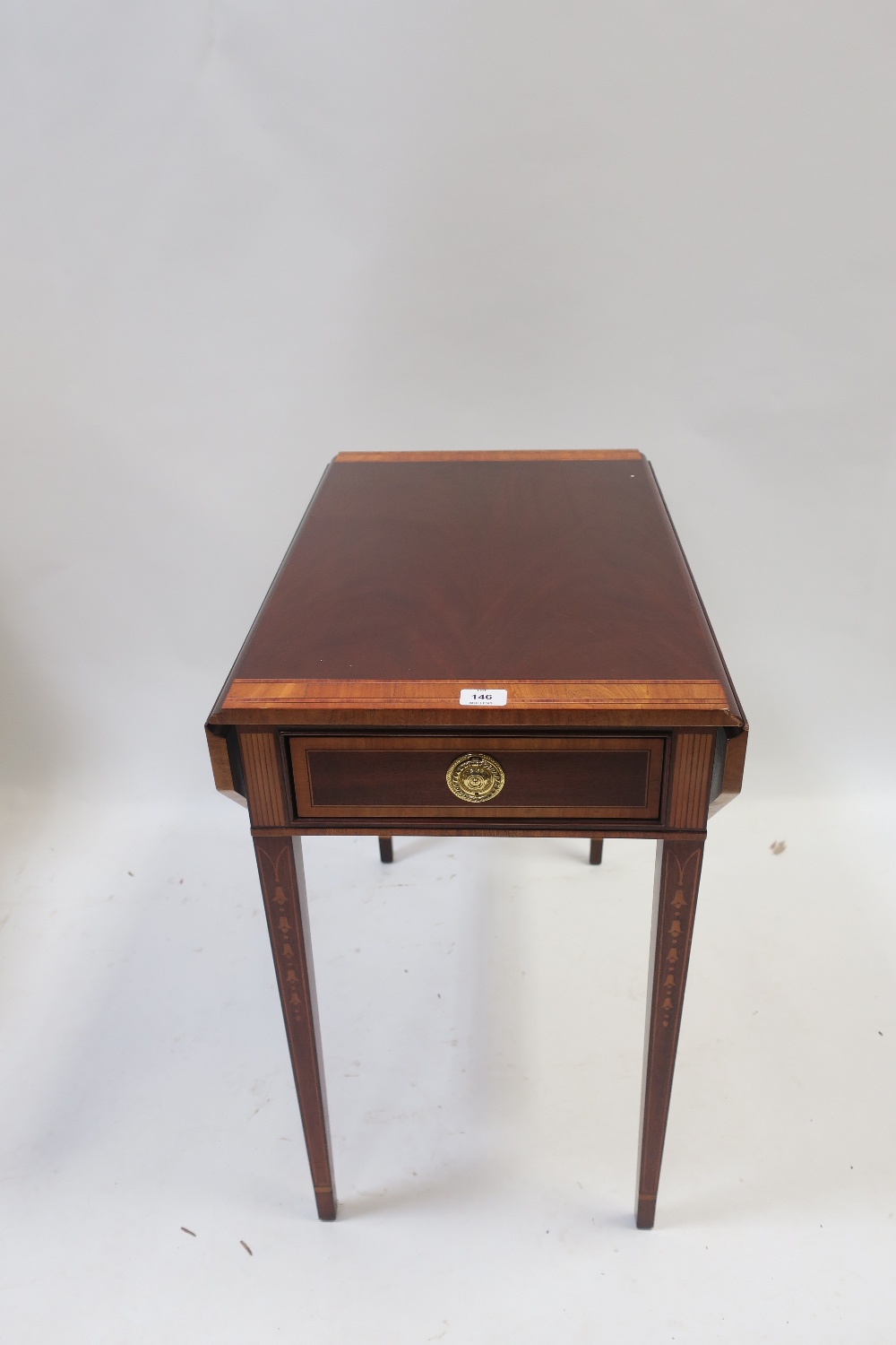 A GEORGIAN STYLE MAHOGANY CROSS BANDED DROP LEAF TABLE the rectangular top with canted corners