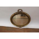 A GEORGIAN STYLE OVAL WALL MIRROR, the frame headed by a foliate cartouche with bevelled plate,