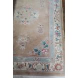 A RECTANGULAR WOOL RUG the beige ground decorated with foliate filled green and cream panels with