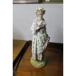 A PAINTED PORCELAIN MODEL OF A DUTCH GIRL, shown in period dress on oval base,