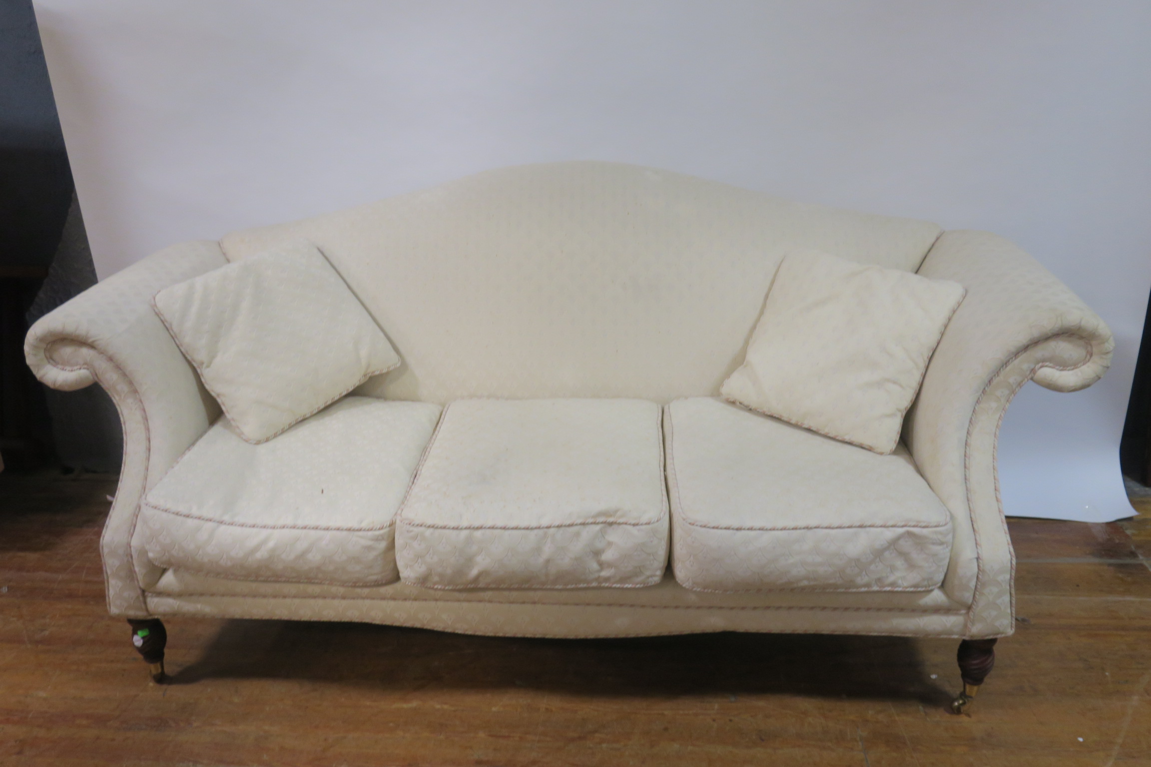A MAHOGANY FRAMED HUMP BACKED SOFA the cream upholstered back and scrolled sides with loose cushion