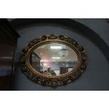 A CONTINENTAL GILT FRAMED MIRROR, the oval plate within a shell and C scrolled pierced frame,