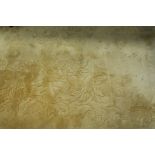 A RECTANGULAR WOOL RUG, the gold ground embossed with foliate motifs and white fringing,