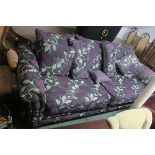 A MODERN THREE SEATER SETTEE, with floral upholstery on scroll arms with loose cushions,