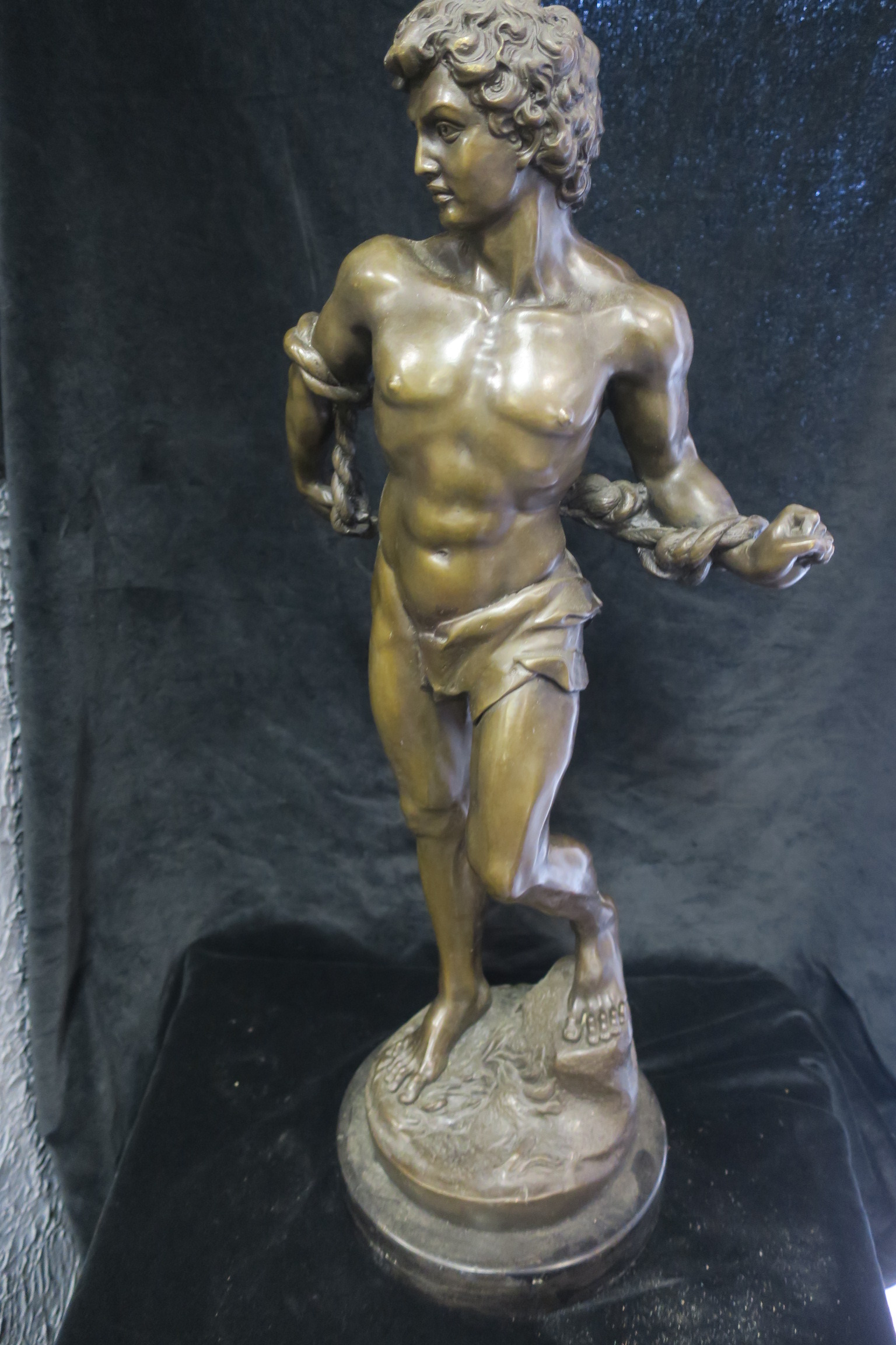 A BRONZE FIGURE, modelled as David, shown standing on a naturalistic base with marble plinth,