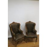 A PAIR OF MAHOGANY FRAMED CONTINENTAL STYLE WING BACKED ARMCHAIRS with scrolled and foliate carved