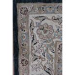 A RECTANGULAR WOOL RUG the cream ground with a rectangular green foliate filled panel with