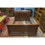 AN EMPIRE STYLE MAHOGANY BED, with panelled head board between shaped scrolled sides,