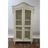 A CONTINENTAL STYLE WHITE PAINTED DISPLAY CABINET the moulded top above a deep frieze with a pair