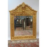 A CONTINENTAL STYLE GILT OVERMANTLE MIRROR the shield shaped frame headed by a foliate cartouche