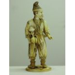 A late 19thC Japanese carved ivory figure of a man holding a spinning top game, height 8.5ins, red