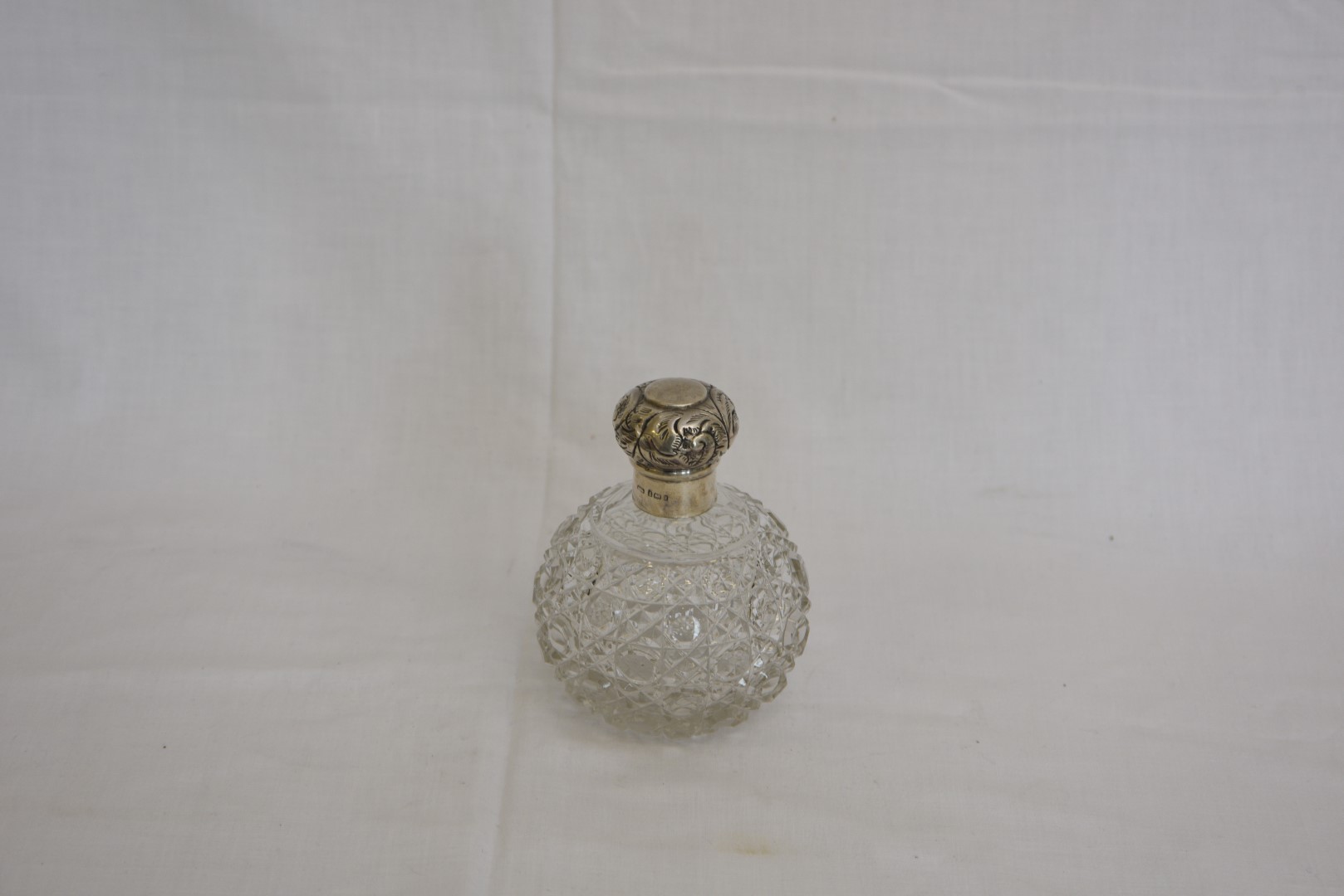 A late Victorian silver mounted glass scent bottle with engraved scroll decoration and cut glass