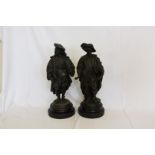 A pair of cast spelter figures depicting scholars, each holding a book, on turned ebonised wooden