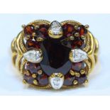 A 9ct gold Mozambique garnet and diamond ring of quatrefoil design, set with a central oval