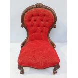 A Victorian walnut spoon back nursing chair with button back, red floral fabric upholstery and