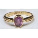 An 18ct gold ring set with an oval pink gemstone, probably a sapphire, 3.42grams