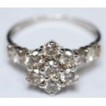 A 9ct white gold diamond cluster ring modelled as a flower and set with eleven RBC diamonds, VS