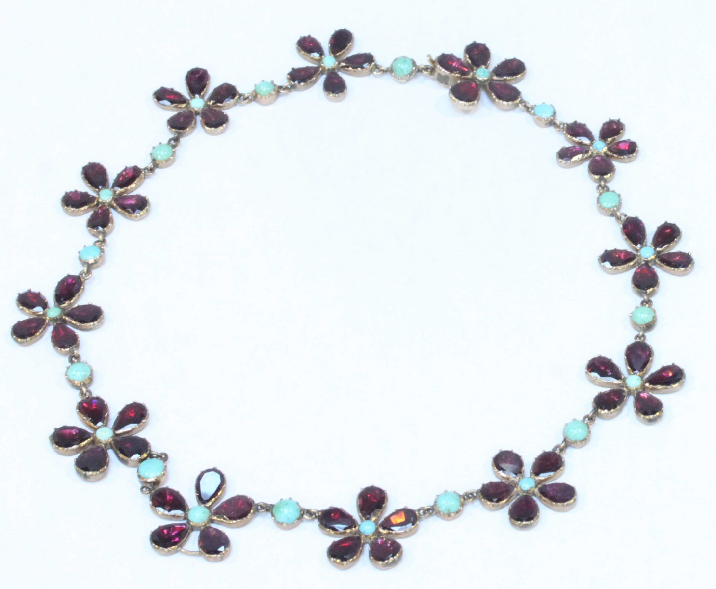 A George III gold, garnet and turquoise necklace modelled as twelve linked five-petal pansy flowers,