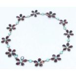 A George III gold, garnet and turquoise necklace modelled as twelve linked five-petal pansy flowers,