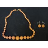 A single row of Coral bead necklace, carved decoration and orange In colour, with matching pair of