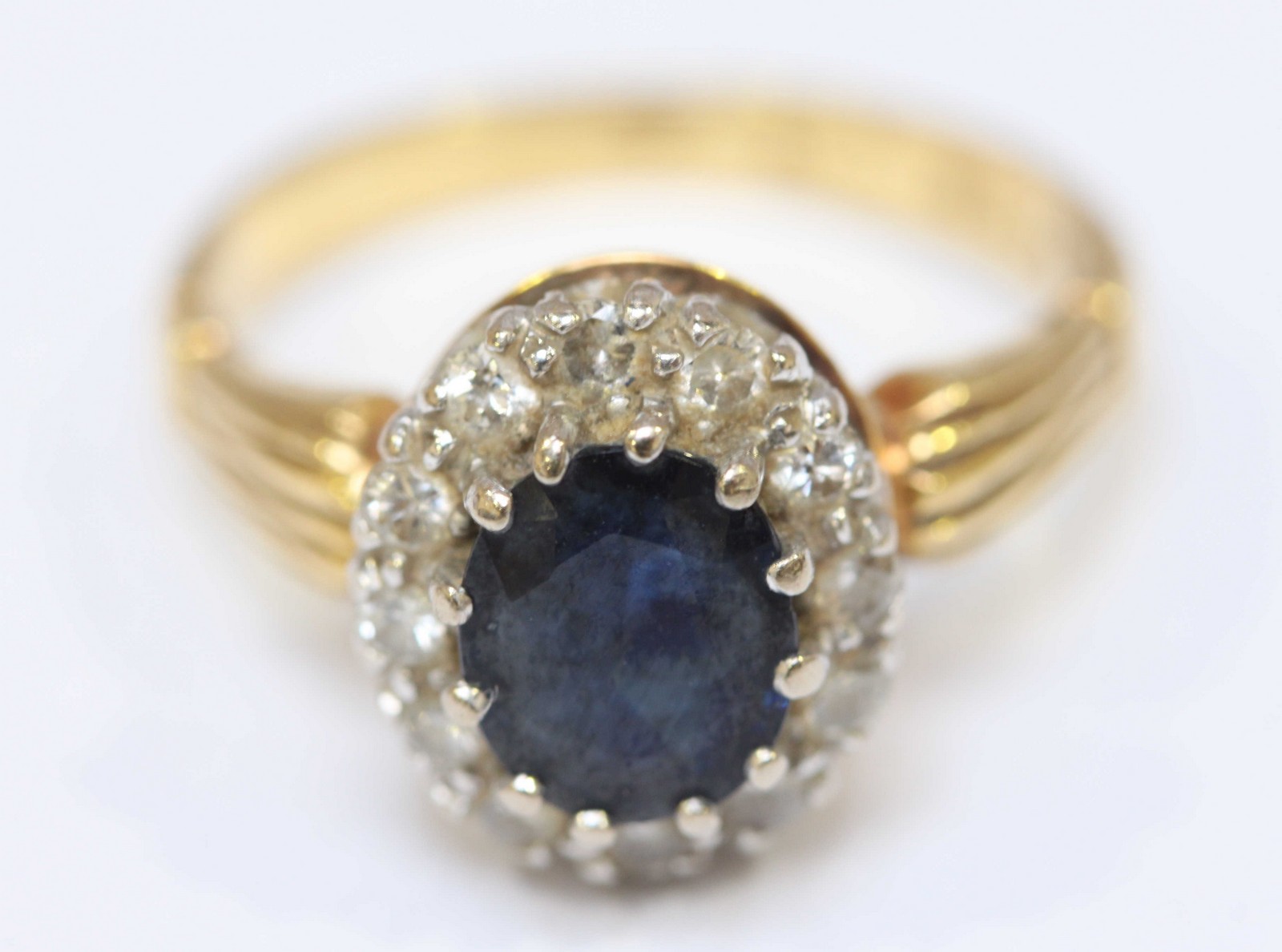 An 18ct yellow gold Sapphire and Diamond ring, the centrally set oval Sapphire surrounded by 12