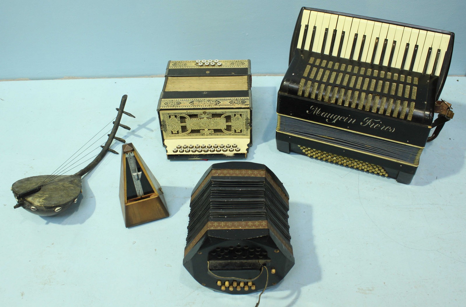 A group of three accordions of varying style, including one by Maugein and one with ornate floral