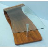 A modern teak laminate coffee table, the curved glass top supported by a cylindrical chrome