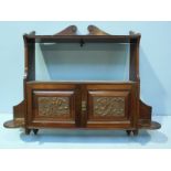 A mahogany wall cabinet, the scrolled top above an open shelf leading to two foliate carved panel