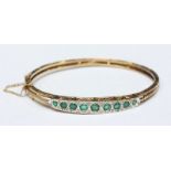 A 9ct gold antique style emerald and diamond bangle, approximate weight 17.9grms.