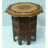An ornately carved hardwood occasional table, the octagonal top decorated with a peacock and