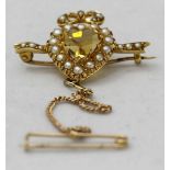 A yellow gold (tests as 14-15ct) brooch, centrally set with a heart shaped citrine and surrounded by