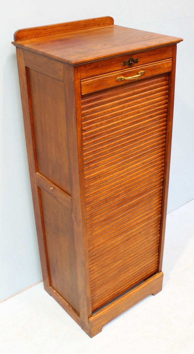 A 1920's oak music cabinet with locking tambour front, opening to reveal multiple wooden trays.