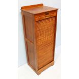 A 1920's oak music cabinet with locking tambour front, opening to reveal multiple wooden trays.