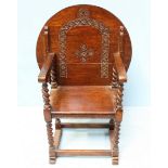 A stained oak monks bench, the circular back with floral carved decoration, folding over to create a