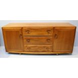 A 1960's elm Ercol sideboard, with three long central drawers, flanked on either side by cupboard