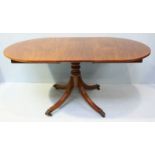 A George III style mahogany extending dining table, raised on a central turned column to four down