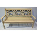 A green painted wooden bench, with shaped and pierced back, slatted bench seat and raised on