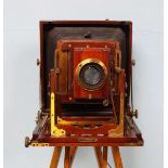 An early 20th century mahogany and laquered brass folding plate camera with adjustable ash tripod