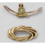 A 9ct gold demi-lune style bar brooch adorned with an Owl, within which is a centrally set Peridot