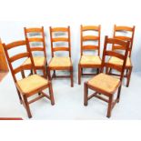 A set of six oak ladder-back chairs with rush woven drop in seats and raised on square supports.