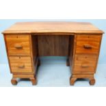 A 20th Century Mukwa wood pedestal desk, the top with concave centre, above two pedestals, each with