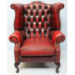 A wing-backed Chesterfield armchair with button back, burgundy leather upholstery and signature