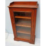 A 19th century mahogany music cabinet with three-quarter galleried top, above a single glazed door