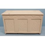 A cream painted oak coffer, the top opening to reveal storage space and with three carved panels