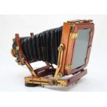 A late 19th/early 20th century folding mahogany bellows plate camera with brass Beck Symmetrical