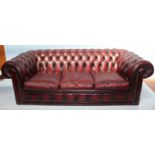 A burgundy leather low back three-seater Chesterfield sofa, with deep button back and sides,