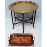 An Oriental circular brass tray on folding wooden stand, the tray engraved with scenes of Elephants,