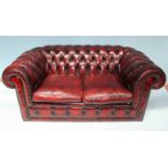 A burgundy leather low back two-seater Chesterfield sofa, with deep button back and sides,