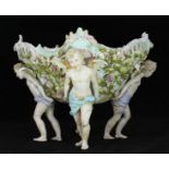 A German porcelain oval centre-piece, with a floral moulded design, supported by four cherubs. (AF)